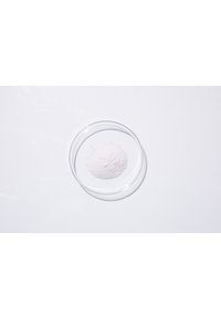 Fine polvere rosa in un piatto di vetro trasparente su una superficie bianca, con una consistenza liscia e una distribuzione uniforme.