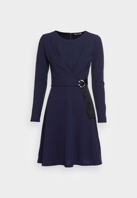 Mörkblå klänning med långa ärmar, med en omslag design, en åtdragen midja med ett svart bälte och metallring som accent, och en något utsvängd kjol.