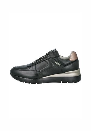 Zapatilla negra de cuero con un acabado texturizado, cuello acolchado, acentos plateados y una suela de goma gruesa. Presenta paneles contorneados y cordones.