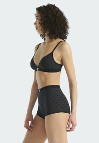 Zwarte bralette en hoog getailleerde slipset met een herhalend bladmotief, een gladde textuur en dunne bandjes met logo-accenten.