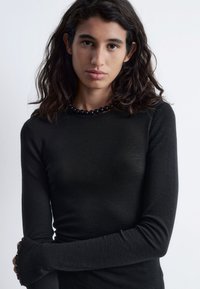 Langärmliges schwarzes Oberteil aus weichem Stoff mit taillierter Passform, rundem Halsausschnitt und leicht ausgestelltenden Bündchen.