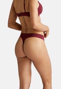 Ensemble bikini bordeaux composé d'un tissu lisse et extensible. Le soutien-gorge dispose de bretelles réglables et d'une fermeture à clip ; le bas offre une couverture minimale.
