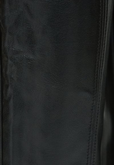 Czarny skórzany materiał o teksturowanej powierzchni, ukazujący drobne wzory ziaren i gładkie wykończenie wzdłuż krawędzi i szwów.