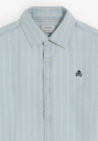 Hellblaues Hemd mit Knopfleiste und weißen vertikalen Streifen, Kragen und kleinem dunkelblauem Totenkopf- und Knochen-Logo auf der Brust.