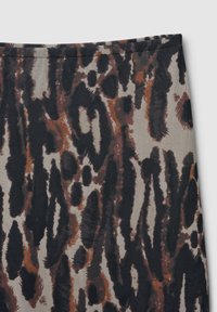 Nahaufnahme eines Stoffs mit abstraktem Tiermotiv in Schwarz-, Braun- und Beigetönen, mit sichtbaren Nähten entlang der oberen Kante.