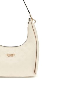 Hobo tas gemaakt van beige gestructureerd synthetisch materiaal met reliëfpatronen, voorzien van een gouden logo en een afneembare zwarte schouderband.