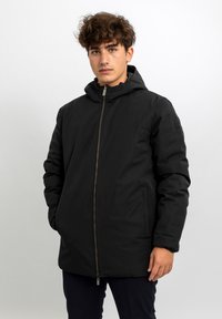 Giacca imbottita nera con zip frontale, cappuccio regolabile e tasche laterali. Caratterizzata da una texture liscia e opaca e da un branding minimale.