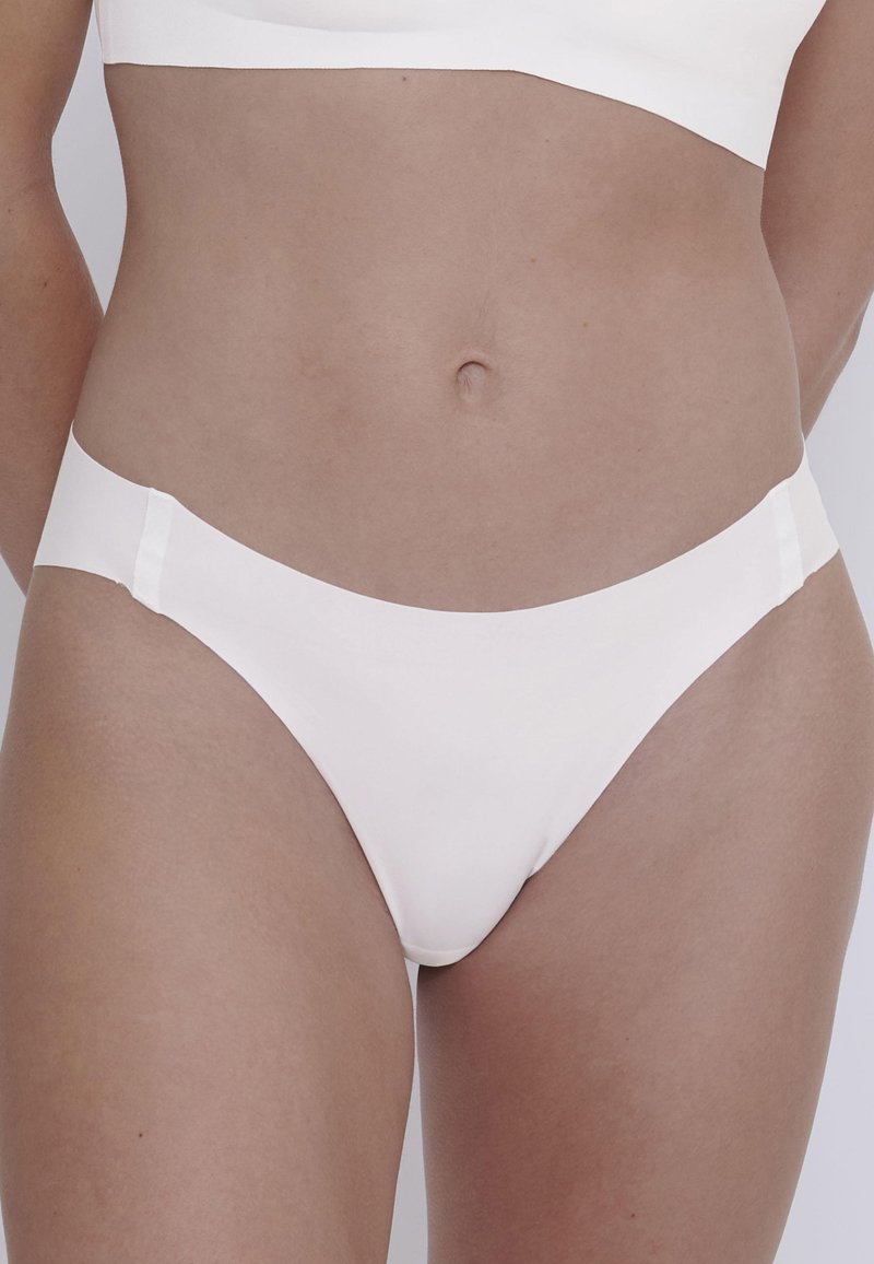Bikini in cotone bianco caratterizzato da una texture liscia, aperture per le gambe a taglio alto e un design minimalista con dettagli in vita elasticizzati.