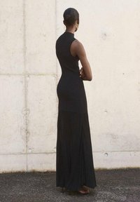 Vestito nero senza maniche con corpetto aderente e gonna lunga a flusso. Tessuto morbido con una sottile trama e design lunghezza caviglia.
