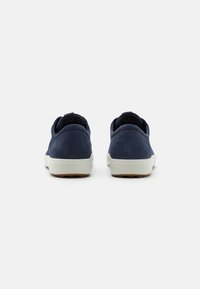 Navy suede sneakers with a textured finish, featuring a white rubber sole and heel accents. Simple, low-profile design.