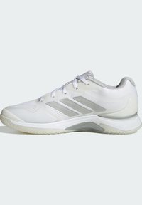 Biały but sportowy z siateczkową cholewką i syntetycznymi nakładkami. Posiada trzy srebrne paski oraz teksturowaną gumową podeszwę zapewniającą przyczepność.
