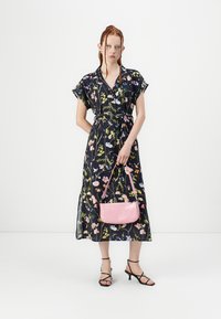 Maxikjole med blomstertrykk og korte ermer, innsnevret midje, i marineblått med rosa og grønne detaljer; kombinert med en liten rosa crossover-veske.