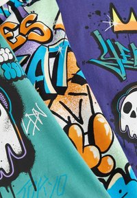 Brightly colored fabric with graffiti-style graphics including skulls, crowns, and bold stylized text in blue, orange, purple, black, and white.