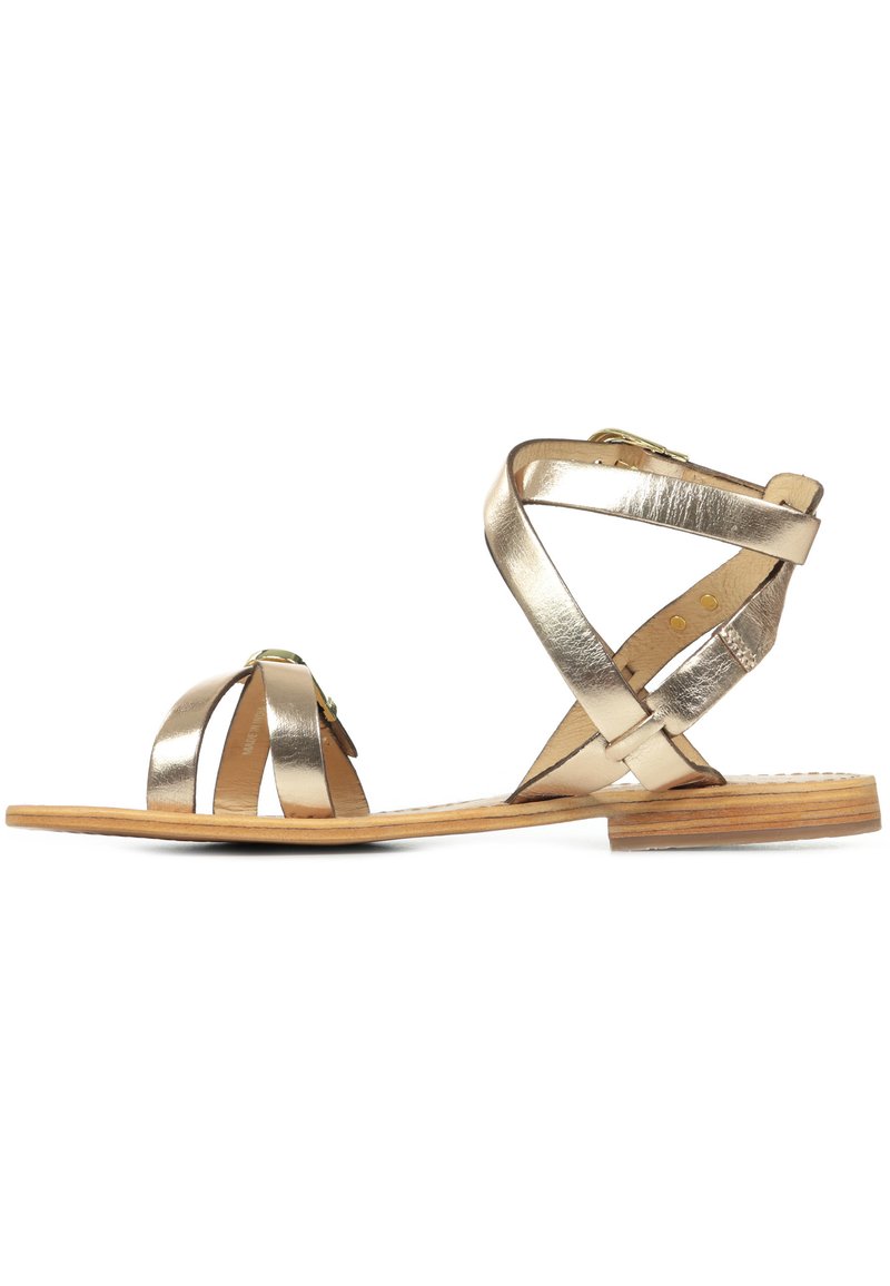 Sandales métalliques dorées avec des sangles croisés, un bout rond, une semelle en bois et une fermeture à boucle pour un meilleur ajustement et un soutien optimal.