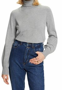 Pull à col roulé gris à manches longues, confectionné en tissu doux, associé à un jean en denim bleu taille haute avec une coupe et un design classiques.