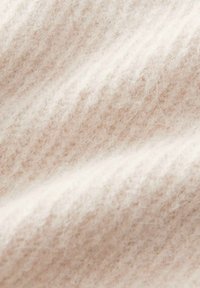 Tessuto di lana morbido color crema con una texture pelosa e un motivo a maglia visibile, mostrato in dettaglio ravvicinato.