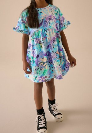 Robe à manches courtes dans des couleurs pastel, arborant un motif abstrait avec des cœurs et des formes, en tissu léger, jusqu'aux genoux. Baskets noires.