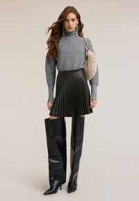 Grå ribbstickad polotröja, plisserad svart minikjol i konstläder och svarta knähöga stövlar med klack. Mjuk pälsväska som accent.