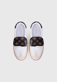 Baskets blanches avec sangle en cuir noir, présentant des détails en motif doré et une semelle en caoutchouc. Lacets à l'avant et marque "GUESS" à l'intérieur.
