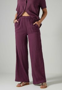 Ensemble deux pièces léger et texturé de couleur violette, comprenant un haut à manches courtes avec une poche et un pantalon à taille élastique avec des poches latérales.