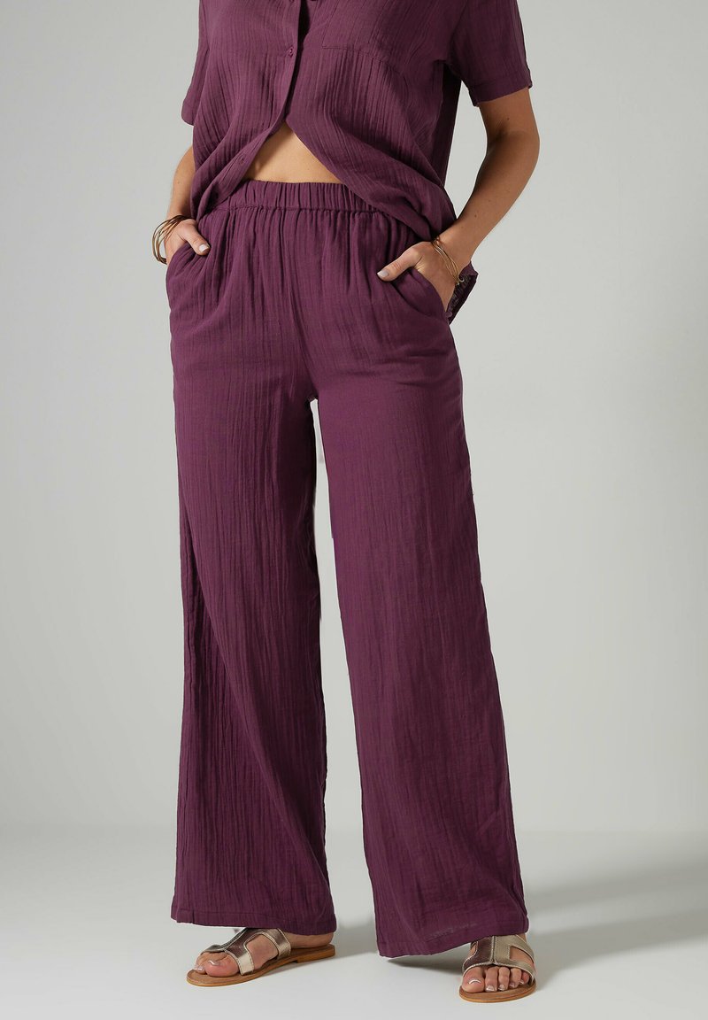 Ensemble deux pièces léger et texturé de couleur violette, comprenant un haut à manches courtes avec une poche et un pantalon à taille �élastique avec des poches latérales.