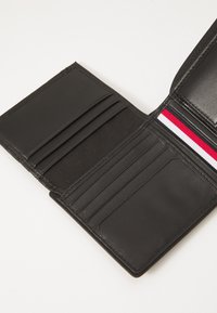Black leather wallet with multiple card slots, smooth texture, and a red, white, and blue striped accent. Open, showcasing interior compartments.