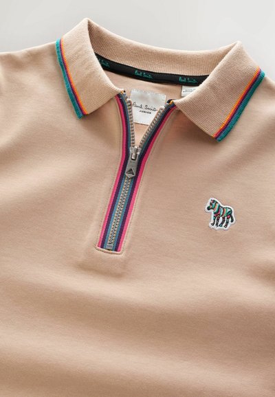 Beige Poloshirt mit einem Reißverschluss und einem gestreiften Kragen in Blau, Grün und Rot. Gesticktes Zebra-Logo auf der Brust. Glatte Textur.