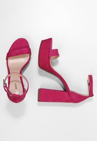 Roze suède plateauhakken met een brede band over de tenen, enkelbandje met gesp en een stevige vierkante hak. Glad binnenwerk.