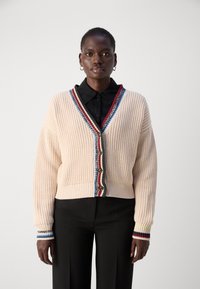 Cardigan a coste avorio con scollo a V profondo, bordi testurizzati multicolori e chiusura con bottoni. Presenta maniche lunghe con polsini a contrasto.