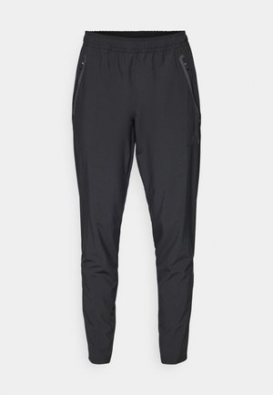 Zwarte sportieve broek van lichtgewicht materiaal met een elastische tailleband, taps toelopende benen en zijzakken met ritsen.