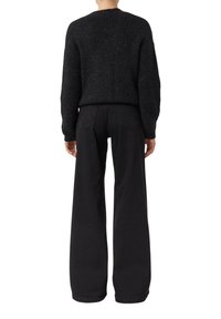 Czarny dziany sweter o fakturowanym wykończeniu, zestawiony z czarnymi, szerokimi spodniami. Oba elementy cechują się jednolitym kolorem z minimalnymi zdobieniami.
