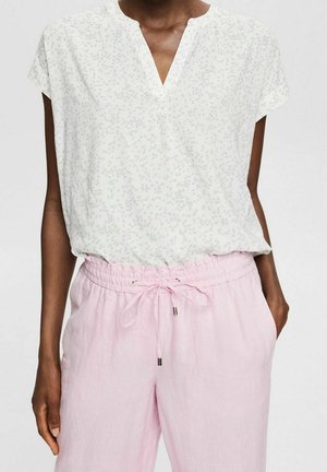 Top leggero a maniche corte in off-white con una sottile stampa floreale in lavanda e verde, caratterizzato da una scollatura a V e una vestibilità comoda.