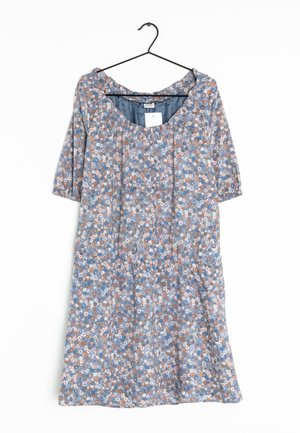 Robe fleurie bleue avec manches bouffantes et boutons sur le devant, suspendue sur un cintre noir contre un fond blanc.