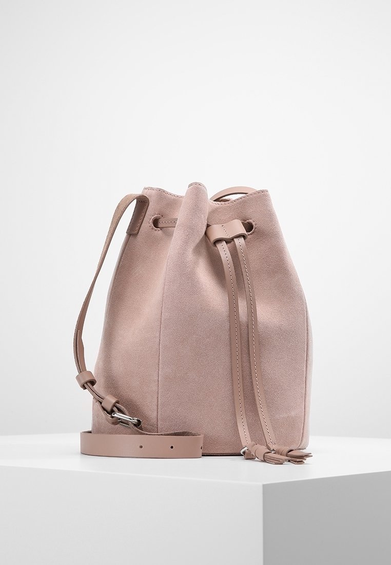 Pink suede bucket bag with a drawstring closure, adjustable strap, and smooth texture. Features simple, clean design and soft contours.