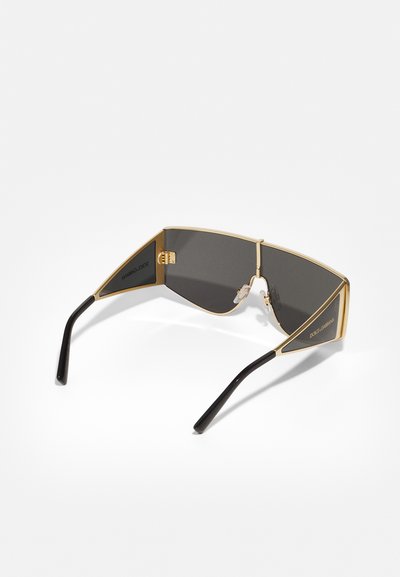 Gold-framed sunglasses with gray lenses, angular design, black temple arms, and nose pads for comfort. Notable logo detail on the frame.