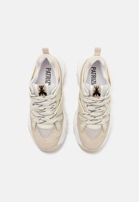 Beige og hvite sneakers med mesh- og semsket overdel, tykk såle og svarte og hvite lisser. Logo på tungen og myke teksturerte detaljer.