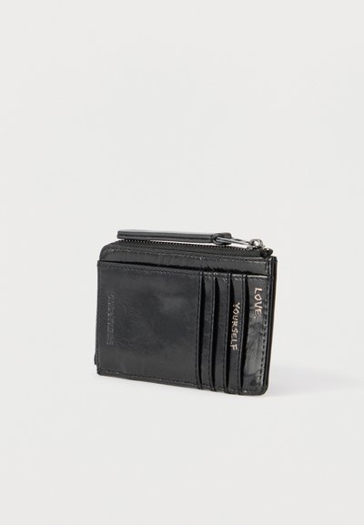 Μαύρο δερμάτινο πορτοφόλι με φερμουάρ και τρεις θήκες για κάρτες, με ανάγλυφο κείμενο "ΑΓΑΠΗΣΕ ΤΟΝ ΕΑΥΤΟ ΣΟΥ" στη δεξιά πλευρά των θηκών.