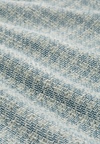 Tessuto intrecciato con un motivo a spina di pesce nei colori azzurro chiaro e crema, che mostra una superficie texture con spessori di filo variabili.
