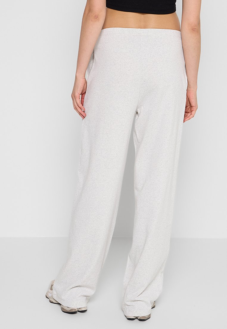 Pantaloni ampi grigi chiari realizzati in tessuto morbido. Presentano una vita elasticizzata e una texture discreta. Nessun motivo o accentuazione visibile.