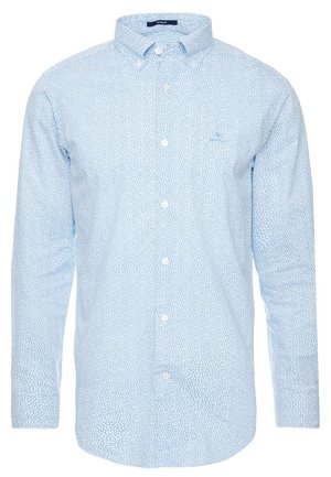Chemise bleu clair à manches longues avec petit motif abstrait à pois bleu foncé et col boutonné.