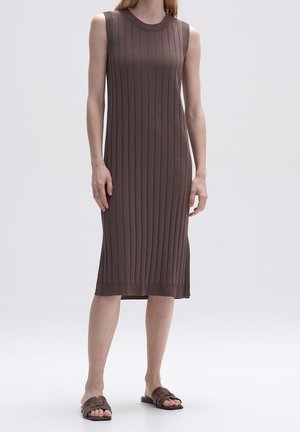 Vestido de punto acanalado marrón sin mangas con escote redondo, que cae justo por debajo de la rodilla. Sandalias planas con un diseño de tiras simple.