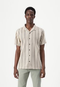 Short-sleeved, collared shirt in beige with vertical stripes in dark and light hues. It features buttons down the front and a relaxed fit.