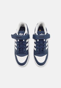 Marineblå sneakers med hvide striber, perforeret tå, polstret krave og velcrolukning. Lavet af læder med gummisål.