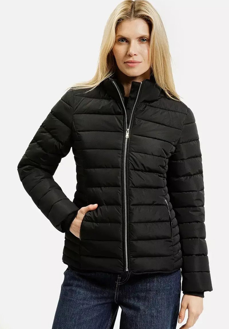 Czarna kurtka puchowa z wysokim kołnierzem, poziomym pikowaniem, zamek błyskawiczny oraz bocznymi kieszeniami. Noszona na ciemną bluzkę i dżinsy.