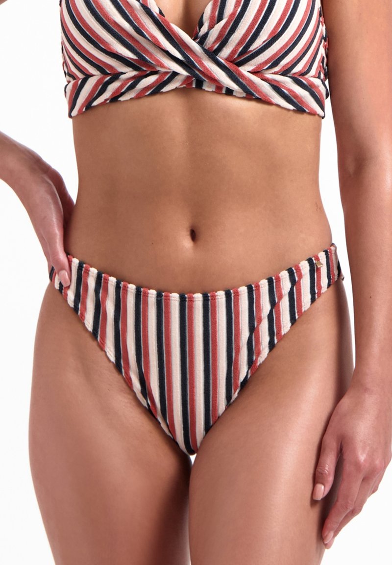 Bikini rayé avec un haut style wrap et un bas taille basse. Les couleurs incluent crème, rouge et bleu marine. Texture douce, avec des accents de couture.