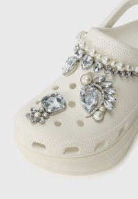 Vita skumtofflor med dekorationer av rhinestones, pärlor och metalliska detaljer i blom- och lövformer; perforerat överdesign.