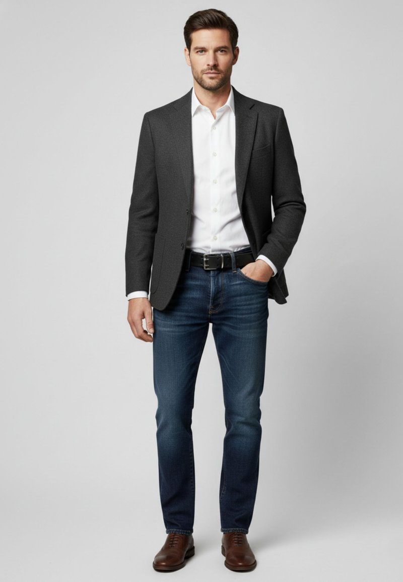 Charcoal grey blazer over a white shirt, paired with dark blue jeans and brown leather shoes. The fit is tailored, with a smooth texture.