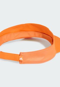 Pomarańczowy sportowy daszek z teksturowanym paskiem, gładkim daszkiem i regulowanym zapięciem. Posiada małe logo z boku. Lekka konstrukcja.