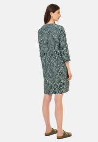 Ruutuja kuvioitu mekko tummansinisellä ja vaalean mintunvihreällä. Ominaisuuksiin kuuluvat kolme neljäsosaa hihat ja rento istuvuus, valmistettu kevyestä kankaasta.