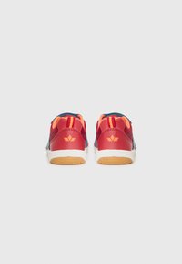 Baskets rouges et bleues en matériaux en maille et en cuir, avec des accents orange et une semelle en gomme texturée. La vue arrière montre un détail de logo simple.